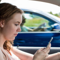 woman demonstrating three types of distracted driving by texting while driving