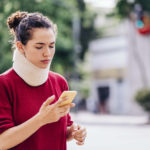 young woman with a personal injury wearing a neck brace outdoors